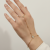chaîne de main dorée en acier inoxydable, un bijou raffiné qui relie délicatement un anneau à un bracelet, orné de perles dorées et de pierres lumineuses