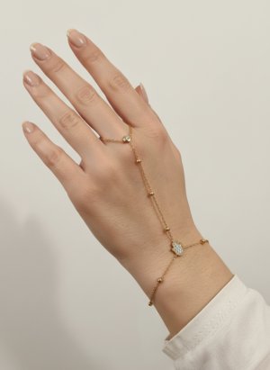chaîne de main dorée en acier inoxydable, un bijou raffiné qui relie délicatement un anneau à un bracelet, orné de perles dorées et de pierres lumineuses